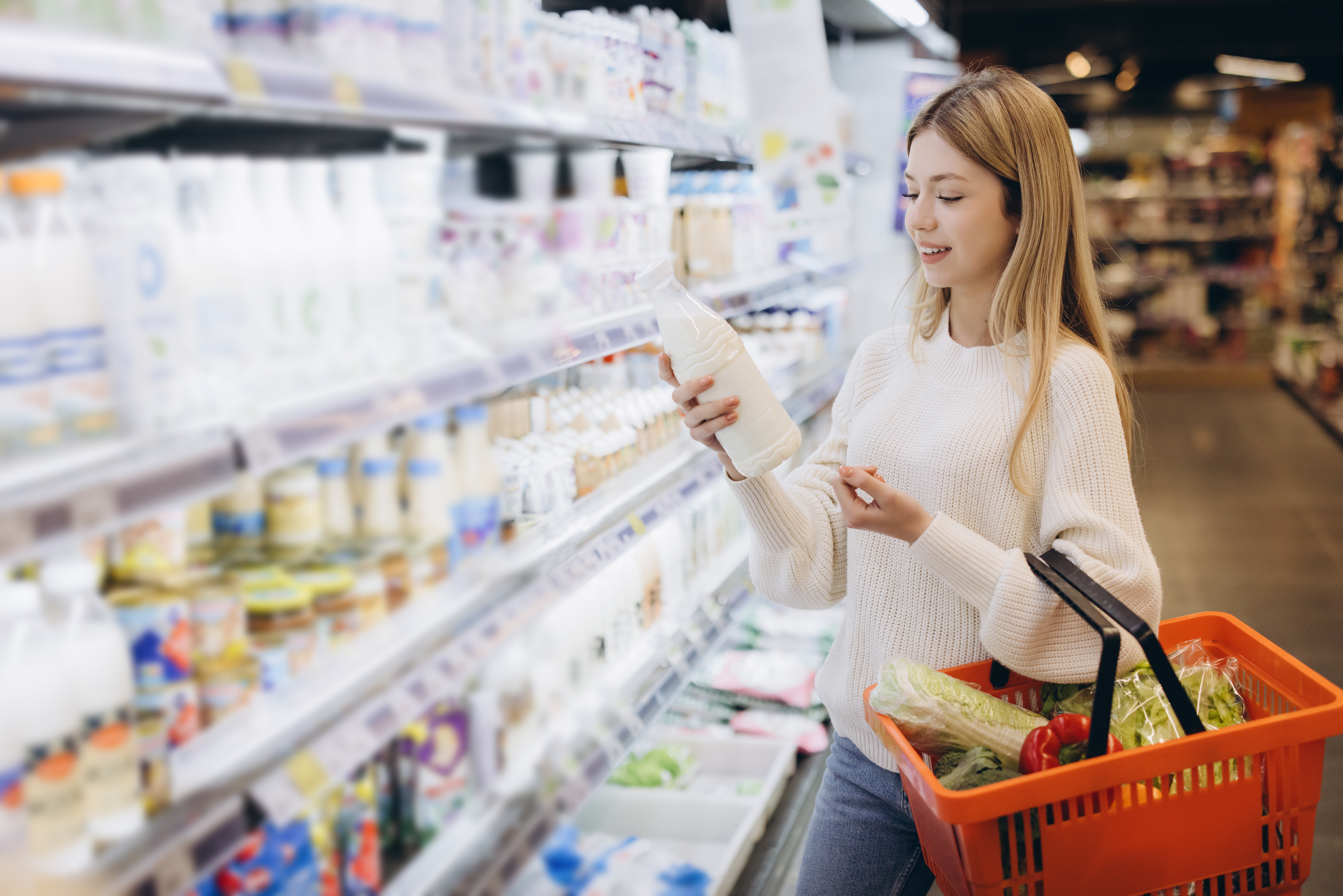 Young,Woman,Shopping,For,Groceries,,Holding,Milk,Bottle,And,Orange Por qué incluir lácteos en la cesta de la compra diaria