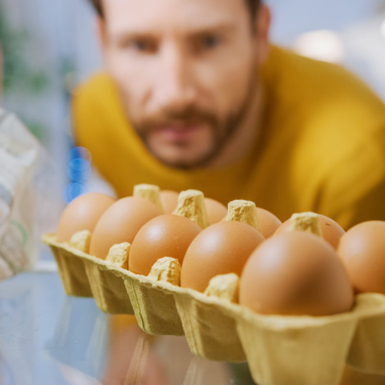Shot from Inside the Kitchen Fridge: Handsome Man Opens Fridge Door, Looks inside and Thinks to Take Eggs from the Eggs Box. Point of View POV Shot from Refrigerator full of Healthy Food