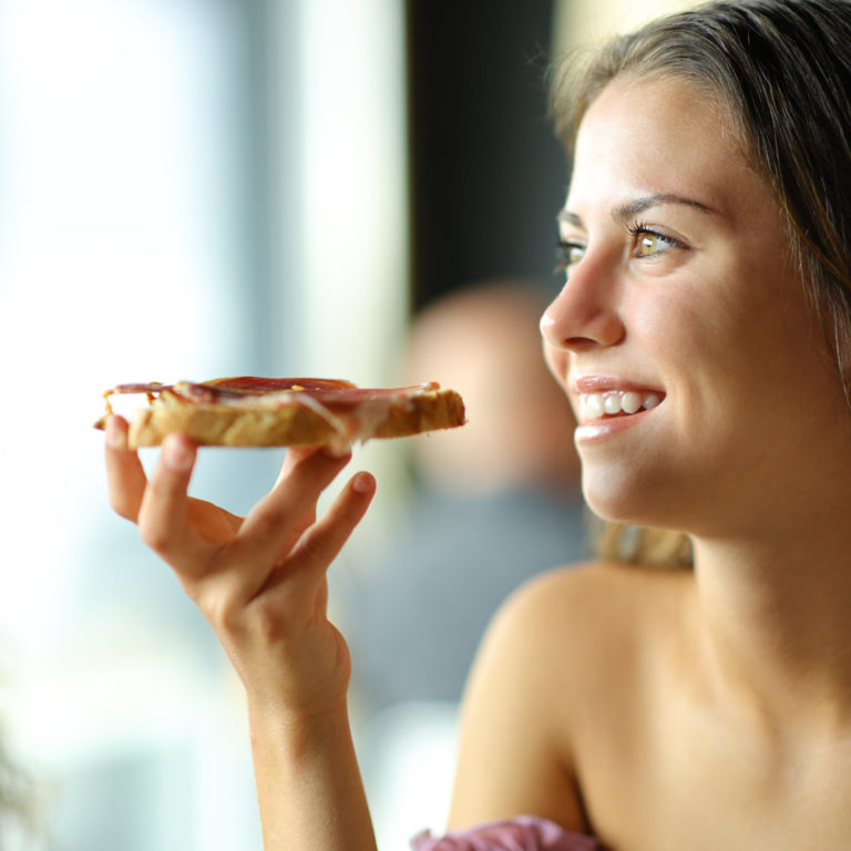 Mujer comiendo una tostada con jamón